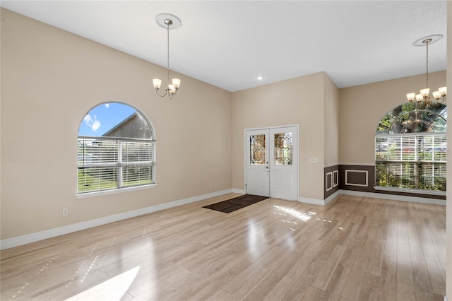 foyer featuring plenty of natural light, a notable chandelier, and light hardwood / wood-style flooring