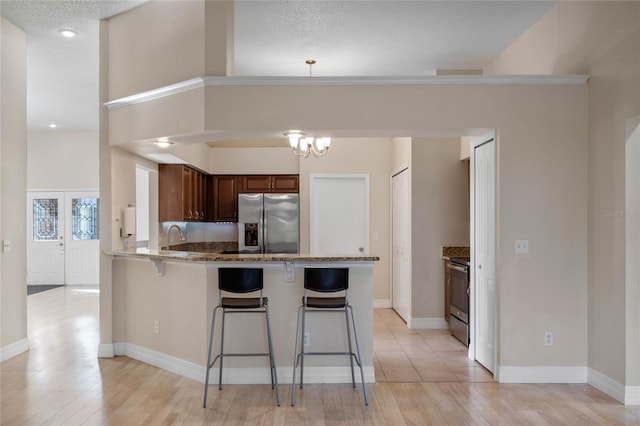 kitchen featuring stainless steel appliances, a kitchen bar, light wood-type flooring, and kitchen peninsula