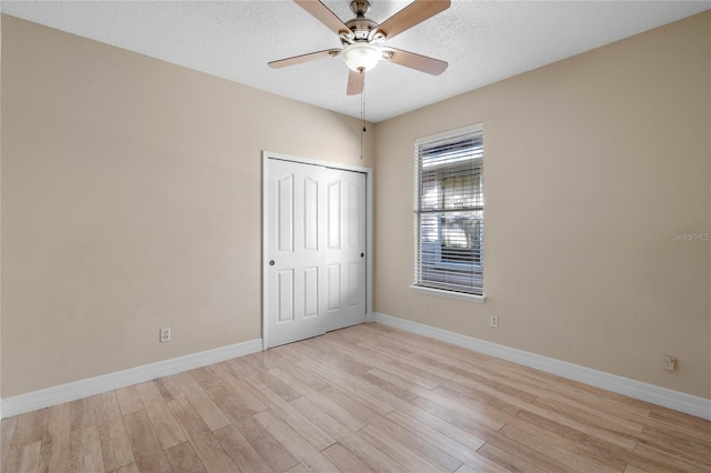 unfurnished bedroom with a closet, light hardwood / wood-style floors, a textured ceiling, and ceiling fan