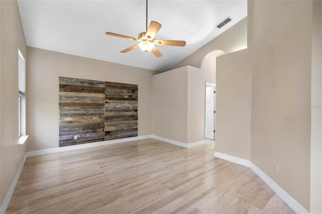 spare room with ceiling fan, vaulted ceiling, light hardwood / wood-style floors, and a textured ceiling