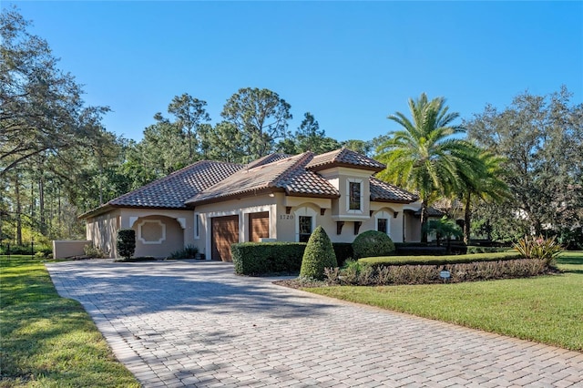 mediterranean / spanish home featuring a front lawn and a garage