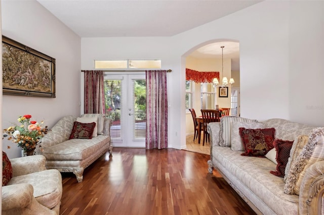 living room with dark wood-type flooring, french doors, and an inviting chandelier