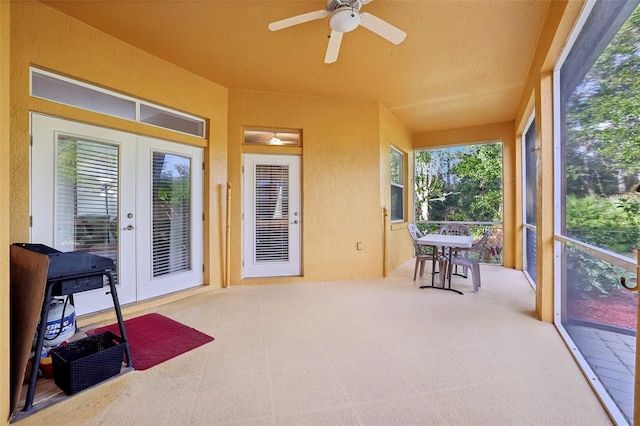 sunroom / solarium with ceiling fan, french doors, and a healthy amount of sunlight