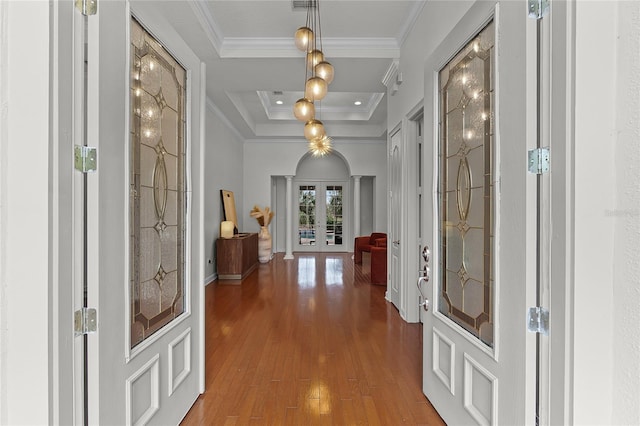 hallway featuring hardwood / wood-style flooring, a raised ceiling, ornamental molding, and french doors