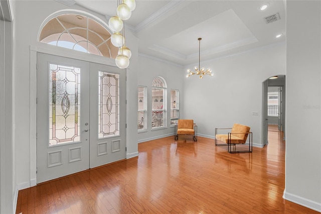 foyer with hardwood / wood-style floors, an inviting chandelier, french doors, and ornamental molding