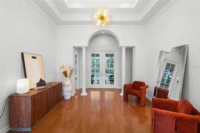 interior space featuring french doors, crown molding, a tray ceiling, light hardwood / wood-style floors, and a chandelier