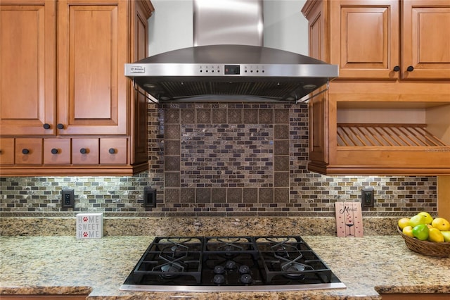 kitchen featuring light stone countertops, black gas cooktop, tasteful backsplash, and wall chimney exhaust hood