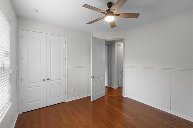 unfurnished bedroom with ceiling fan, dark wood-type flooring, and a closet