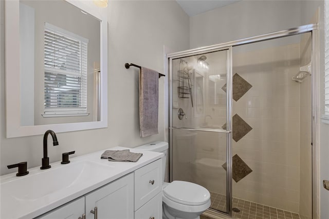 bathroom with vanity, toilet, and a shower with door