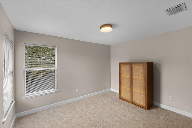 unfurnished bedroom with light carpet and a textured ceiling