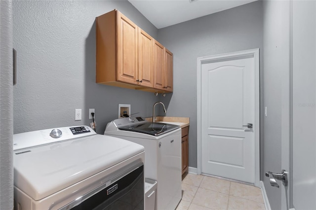 clothes washing area with washing machine and clothes dryer, sink, light tile patterned floors, and cabinets