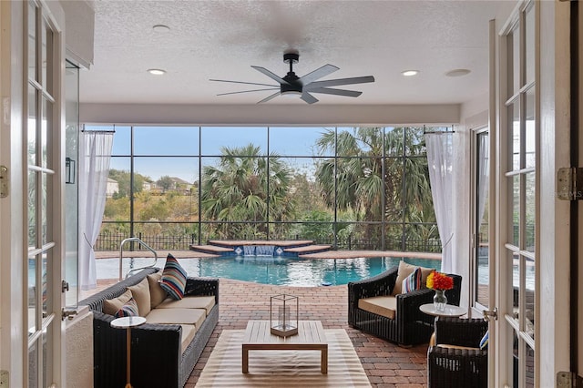 sunroom with ceiling fan, a pool, and french doors