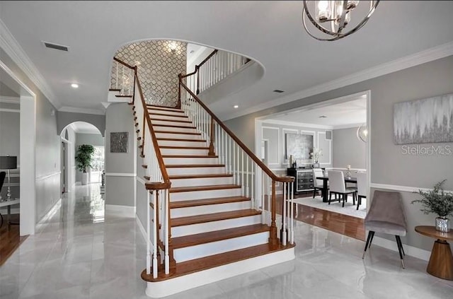 stairway with a chandelier and crown molding