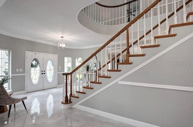 foyer featuring a chandelier, a healthy amount of sunlight, crown molding, and french doors