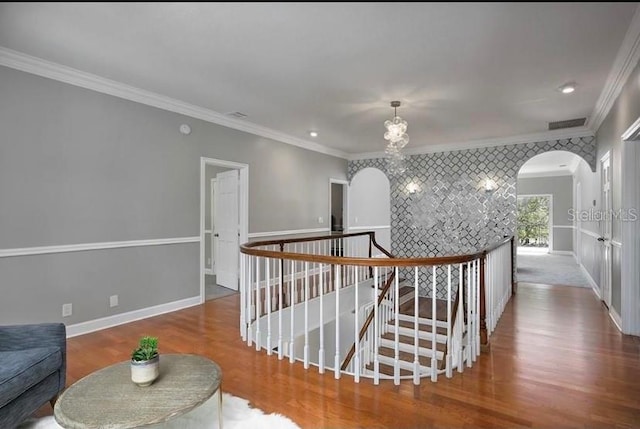 hall featuring an inviting chandelier, wood-type flooring, and ornamental molding