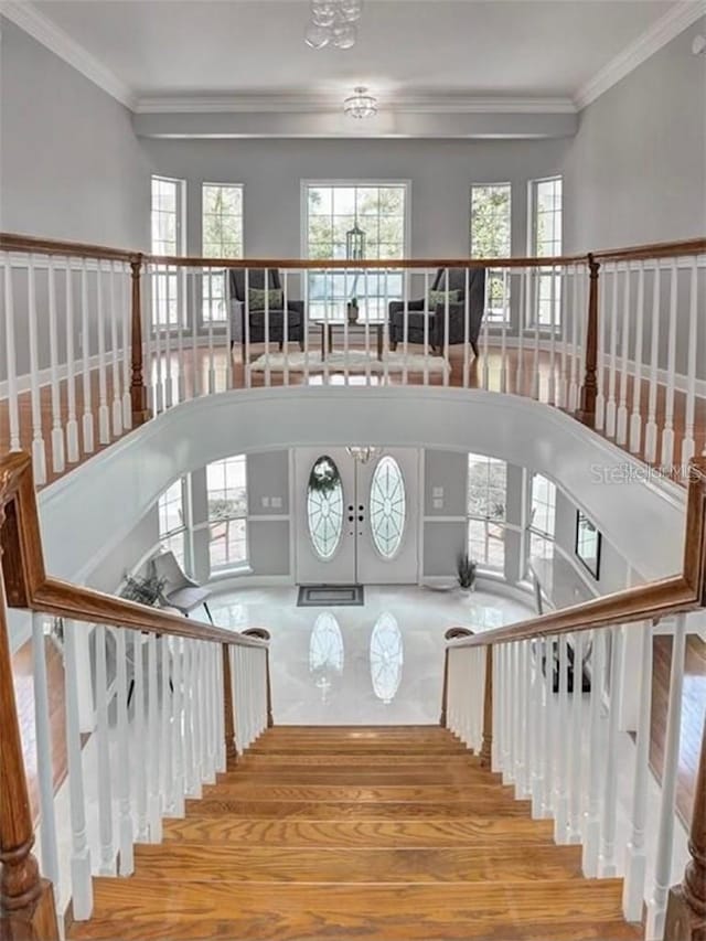 staircase with hardwood / wood-style floors, ornamental molding, and french doors