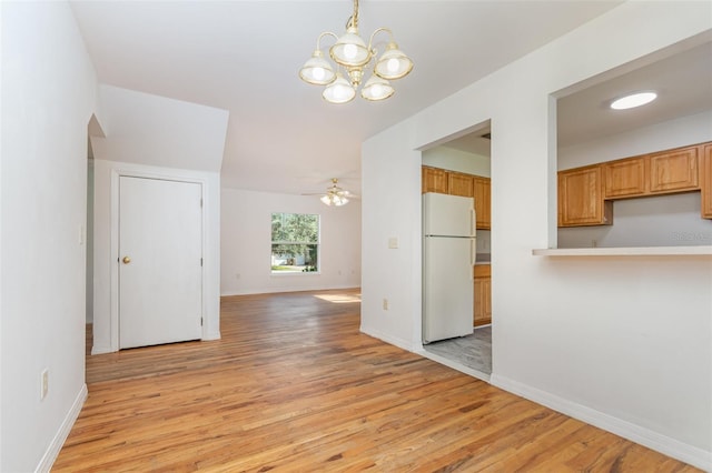 unfurnished dining area with ceiling fan with notable chandelier and light hardwood / wood-style flooring