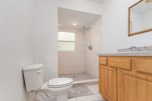 bathroom featuring tile patterned floors, vanity, a tile shower, and toilet