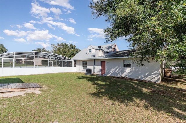 rear view of property featuring glass enclosure and a yard