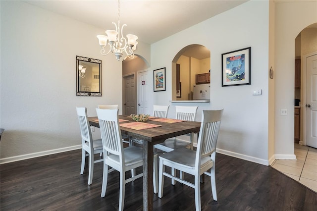 dining area featuring dark wood-type flooring and an inviting chandelier