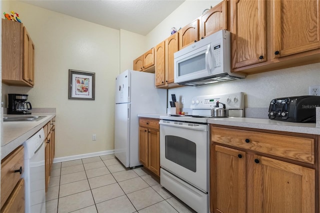 kitchen featuring white appliances, light tile patterned floors, and sink