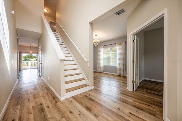 stairway with hardwood / wood-style floors and an inviting chandelier