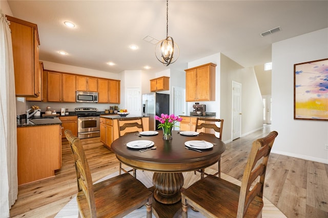 dining space with a notable chandelier, light wood-type flooring, and sink