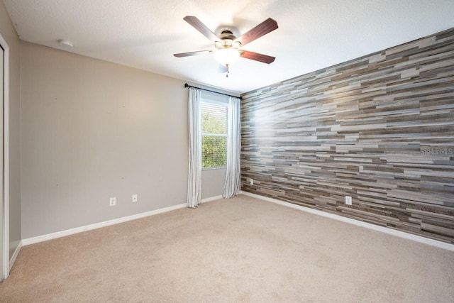 spare room featuring light carpet, ceiling fan, and a textured ceiling