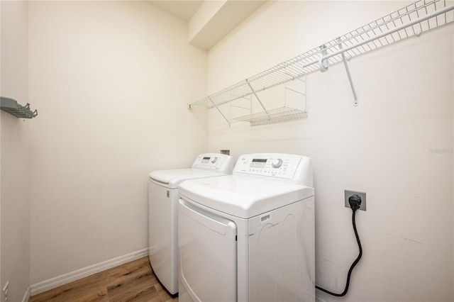 laundry room with washing machine and dryer and light hardwood / wood-style floors