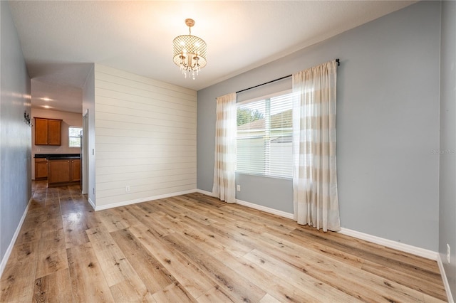 empty room with light hardwood / wood-style floors and a notable chandelier