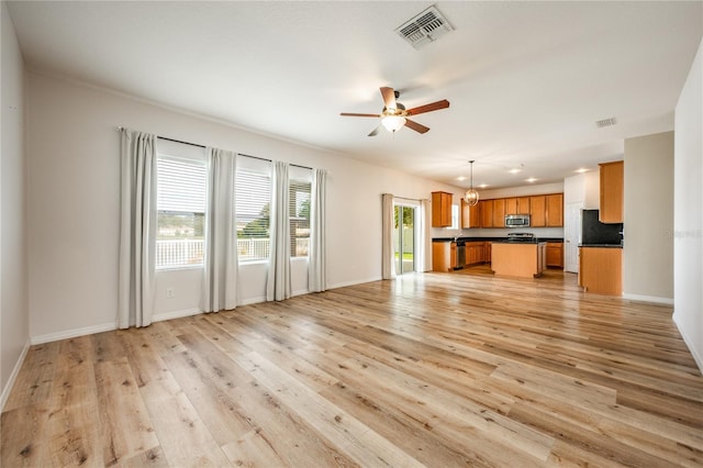 unfurnished living room with ceiling fan with notable chandelier and light hardwood / wood-style floors