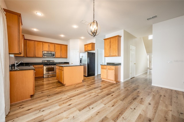 kitchen featuring a kitchen island, light wood-type flooring, hanging light fixtures, and appliances with stainless steel finishes