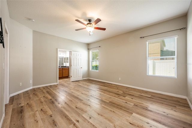 unfurnished bedroom featuring ceiling fan, light wood-type flooring, a textured ceiling, and connected bathroom