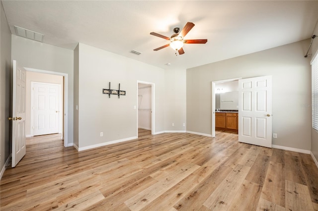 unfurnished bedroom with light wood-type flooring, a spacious closet, and ceiling fan