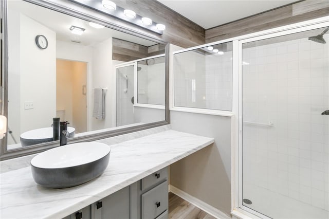 bathroom with walk in shower, vanity, and hardwood / wood-style floors