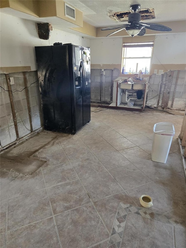 kitchen featuring ceiling fan, black fridge with ice dispenser, and a textured ceiling