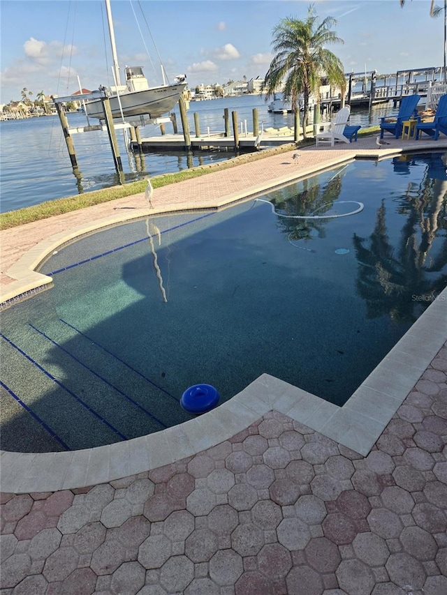 view of swimming pool featuring a water view and a dock