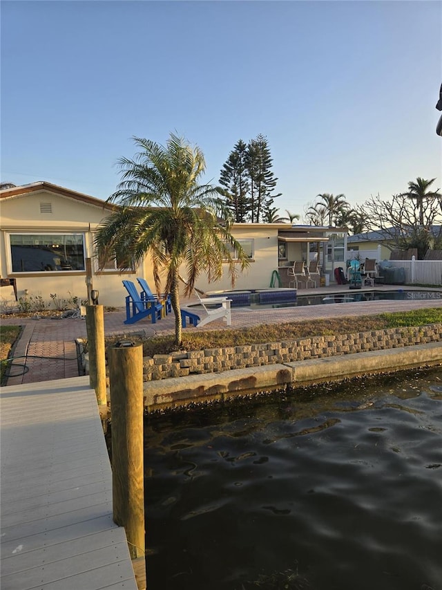 dock area featuring a patio, a water view, and a pool