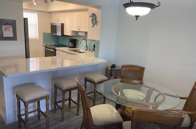 kitchen with white cabinetry, stainless steel electric range oven, kitchen peninsula, and sink