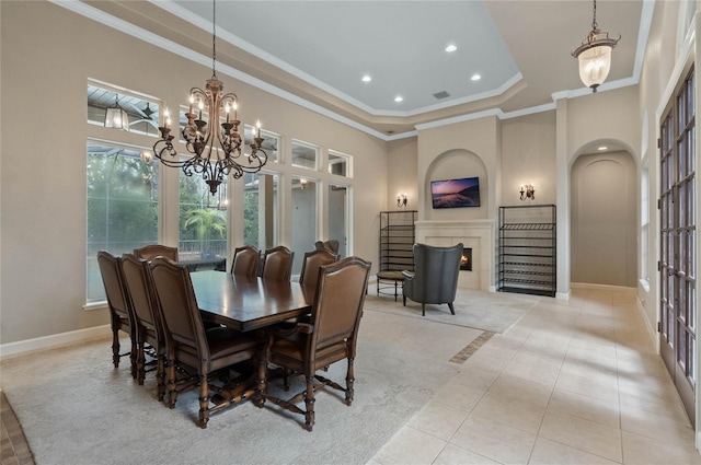 dining room featuring a raised ceiling, a chandelier, crown molding, and light tile patterned floors