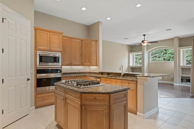 kitchen featuring stainless steel appliances, light tile patterned floors, sink, and a center island