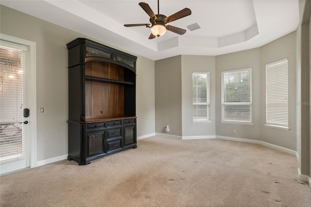 unfurnished living room featuring ceiling fan, light carpet, and a tray ceiling