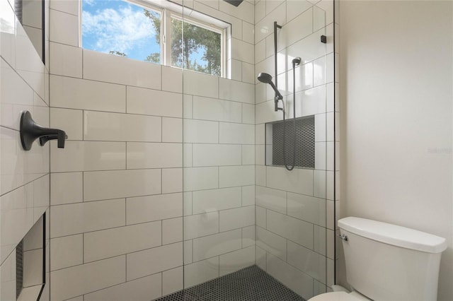 bathroom with a tile shower and toilet