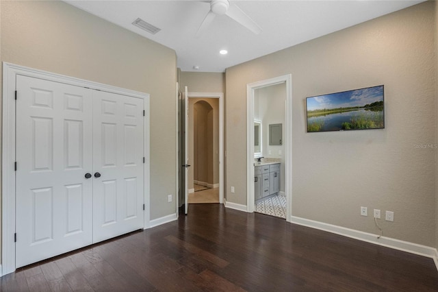 unfurnished bedroom with ceiling fan, connected bathroom, a closet, and dark hardwood / wood-style flooring