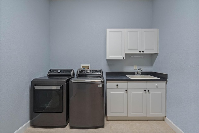 clothes washing area with cabinets, sink, washer and dryer, and light tile patterned floors