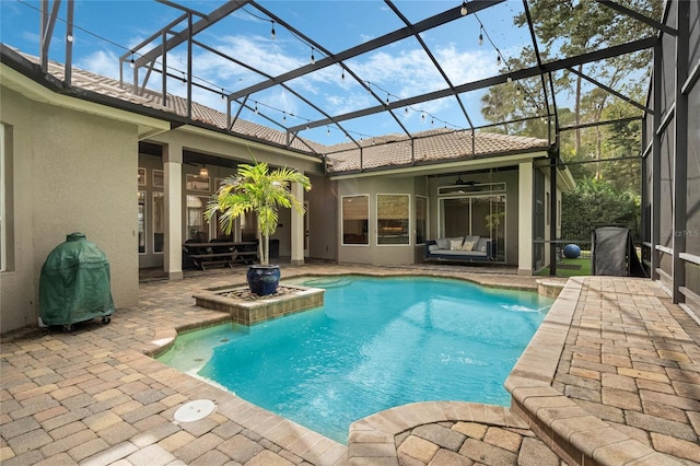 view of swimming pool with glass enclosure, a patio area, and ceiling fan