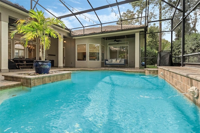 view of swimming pool featuring ceiling fan, glass enclosure, pool water feature, and a patio area