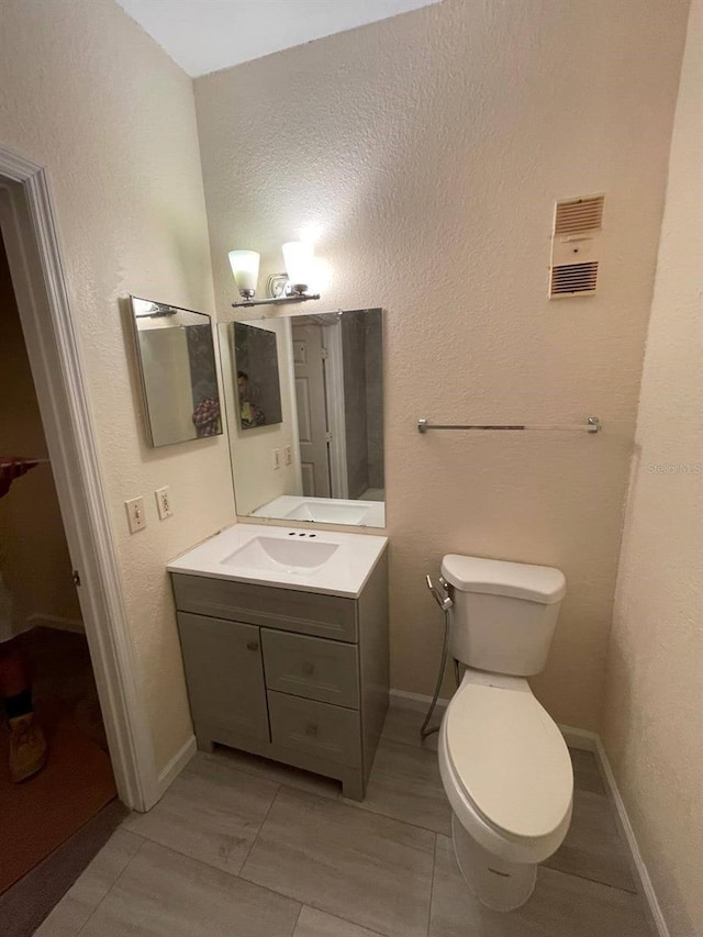 bathroom featuring toilet, vanity, and tile patterned flooring