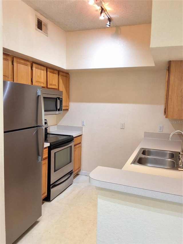 13103 Mulberry Park Dr Unit 817, Orlando, FL 32821 - kitchen featuring stainless steel appliances, rail lighting, a textured ceiling, light countertops, and light floors