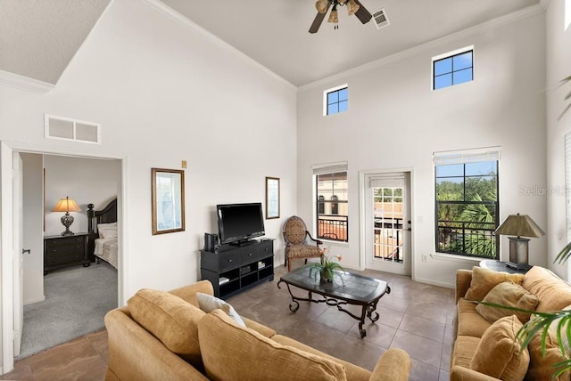 carpeted living room featuring a towering ceiling, ceiling fan, and crown molding